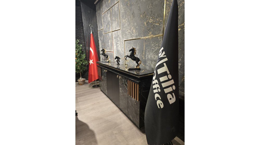 Tilia Gold lüks yönetici masa takımı, siyah mermer desenli tablası ve dikey ahşap çıtalı panelleri ile ofis ortamında A serisi Chester koltuklar ile sergileniyor.